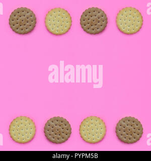 Telaio di un marrone biscotti su un sfondo rosa. Trendy la minima nozione di cibo e dessert. Abstract laici piana, vista dall'alto. Foto Stock