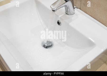 Il lavandino del bagno rubinetto con acqua corrente. Leva singola cromo monoblocco rubinetto miscelatore sul lavandino del bagno. Foto Stock