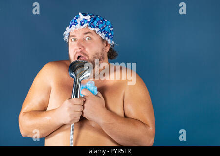 Funny uomo grasso nel tappo blu cantare nella doccia. Il divertimento e la pulizia Foto Stock