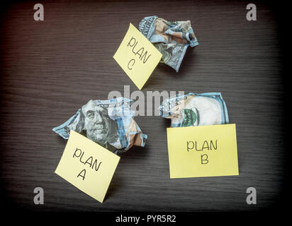 Impossibile business plan A, B e C, coniate banconote di dollari su una scrivania in legno, immagine concettuale Foto Stock