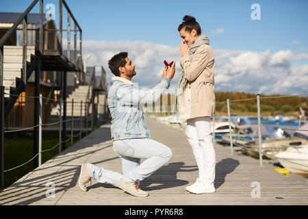 Uomo in amore propone la ragazza sul molo Foto Stock