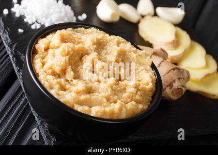 Lo zenzero fresco e aglio pasta o Lahsun Adrak purea in un vaso di ceramica. Messa a fuoco selettiva orizzontale. Foto Stock