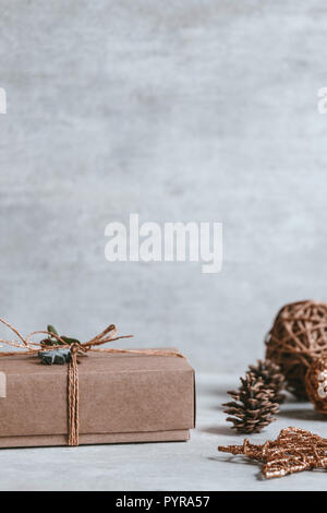 Fatte a mano regalo di Natale o la presente casella avvolti in carta kraft su sfondo di legno. Spazio di copia, biglietto di auguri. Foto Stock