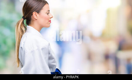 Giovane bella donna che indossa il karate kimono uniforme su sfondo isolato guardando al lato, profilo relax posano con faccia naturale con fiduciosa smil Foto Stock