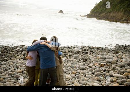 Gruppo di persone huddling in un cerchio su una spiaggia Foto Stock