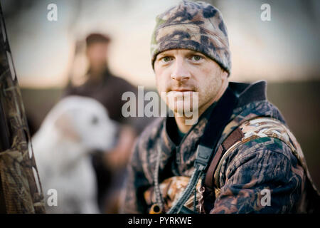 Ritratto di un giovane uomo adulto duck riprese e in possesso di una pistola da un lago. Foto Stock