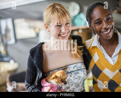 Due ragazze sorridenti e tenendo un chihuahua Foto Stock