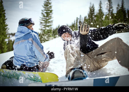 Coppia felice avendo divertimento con le loro tavole da snowboard all'aperto nella neve. Foto Stock