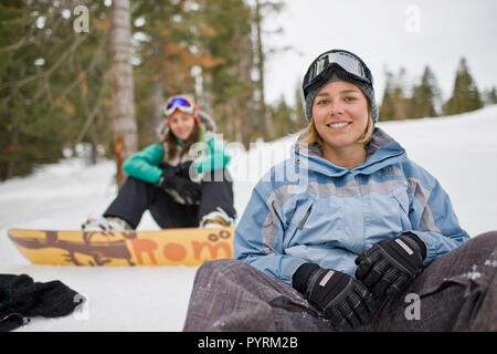 Donna seduta con racchette da neve in montagna Foto Stock