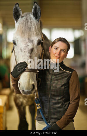 Ritratto di una metà donna adulta e il suo cavallo in una stalla. Foto Stock