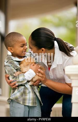 Felice ragazzo tenendo un cucciolo nelle sue braccia accanto a sua madre. Foto Stock