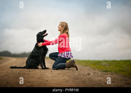 Sorridente ragazza adolescente giocando con il suo cane. Foto Stock