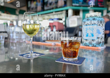 Bevanda miscelata eventualmente un Borbone e di coke o di rum e coca cola lungo con un bicchiere di vino bianco sulla barra a Bud e alley's, Seaside Florida USA. Foto Stock