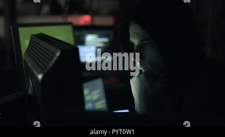 Giovani cool hacker a lavorare al buio con il suo computer e accesso a informazioni private, Cibercriminalità concept Foto Stock