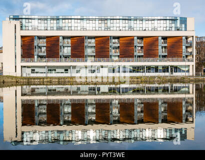 Moderno blocco di appartamenti sul lungofiume, Riva, Leith, Edimburgo, Scozia, Regno Unito simmetrica con la riflessione in acqua di Leith fiume sulla giornata di sole Foto Stock