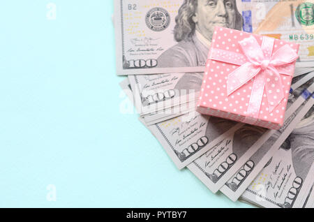 Rosa punteggiato confezione regalo si trova nei pressi di centinaia di dollari su un fondo azzurro. Foto Stock