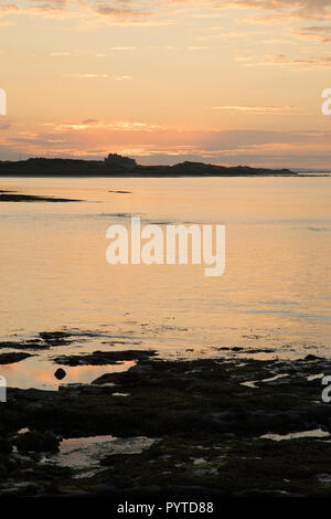 Tramonto al castello di Bamburgh da Seahouses Foto Stock