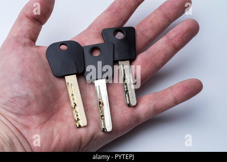 Set di chiavi su Palma umana isolati su sfondo bianco. Tre tasti sul palmo della serratura della porta. Foto Stock