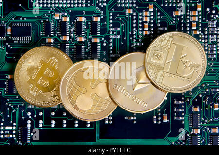 Litecoin, Ripple, Ethereum & Bitcoin monete d'oro che rappresentano cryptocurrenies contro un circuito integrato del computer. Foto Stock