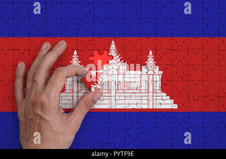 Bandiera della Cambogia è rappresentato su un puzzle che la mano dell'uomo completa per la piegatura. Foto Stock