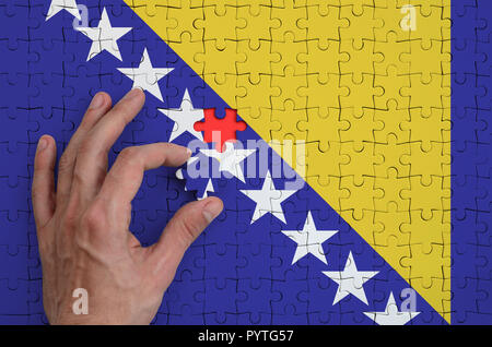 La Bosnia e Erzegovina bandiera è rappresentato su un puzzle che la mano dell'uomo completa per la piegatura. Foto Stock