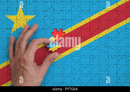 Repubblica democratica del Congo bandiera è rappresentato su un puzzle che la mano dell'uomo completa per la piegatura. Foto Stock