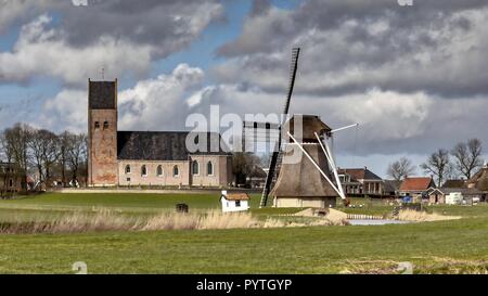 Villaggio con chiesa e storico Mulino sulla campagna frisone. Appena a nord di Leeuwarden, Frisia Foto Stock