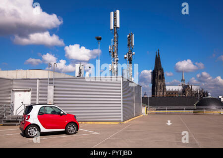 Telefono cellulare a montanti sul parcheggio a più piani della Kaufhof, livello superiore del garage, Smart, vista la cattedrale di Colonia, Germania Foto Stock