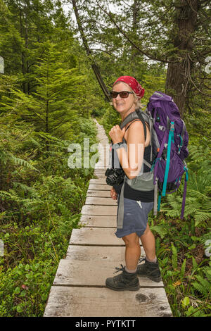 Medio Evo Woman Hiking, Cape Alava Trail, foresta pluviale temperata, vicino a Cape Alava, Pacific Coast, il Parco Nazionale di Olympic, nello stato di Washington, USA Foto Stock