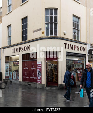 Bath, Regno Unito - 13 Ottobre 2018: la facciata della chiave Timpsons negozio di taglio nell'angolo di West Street e la strada di stallo Foto Stock