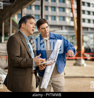 Colleghi di lavoro per discutere i piani in un sito in costruzione. Foto Stock