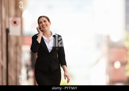 Imprenditrice passeggiate all'aperto parlando di un cellulare. Foto Stock