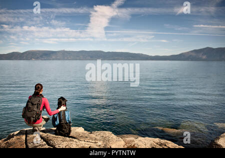 Metà donna adulta guardando il bellissimo lago con il loro cane. Foto Stock