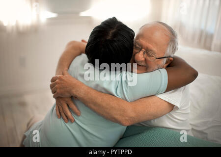 Sorridente uomo senior abbracciando una femmina di infermiere. Foto Stock