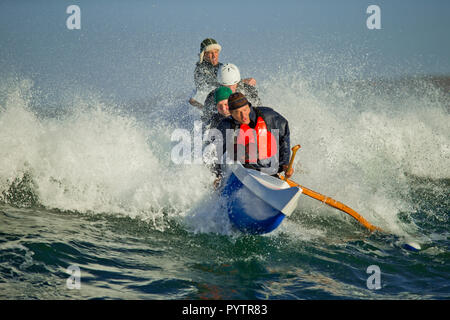 Gruppo di mezza età amici divertirsi su loro canoa in onde dell'oceano. Foto Stock