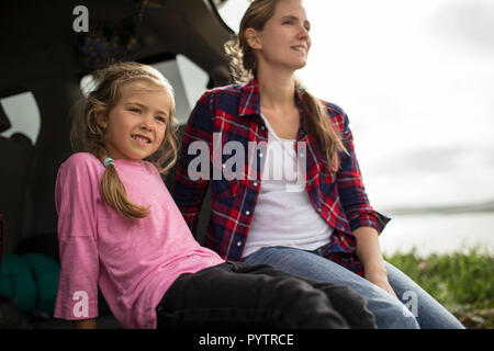 Bambina gode seduti nella parte posteriore della vettura con sua madre e guardando la vista sulla campagna. Foto Stock