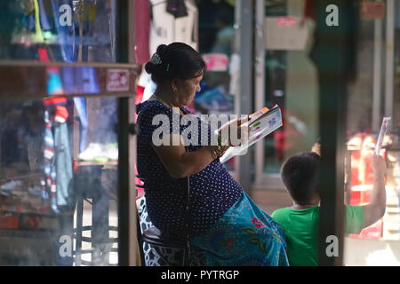 Un etnia nepalese lavoratore migrante dal Myanmar (Birmania) a Bangkok, in Thailandia, che stanno curiosando una rivista Foto Stock