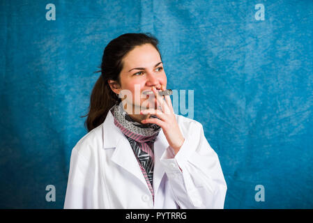 Medico donna fumare una sigaretta e godendo di uno stile di vita poco salutare Foto Stock