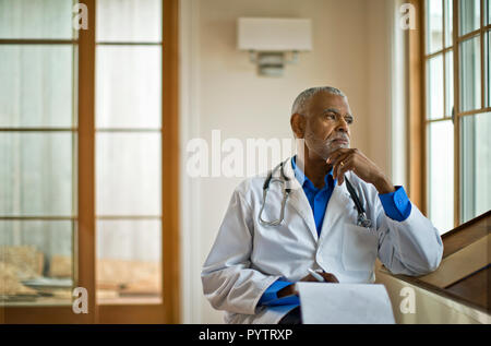 Medico seduto e guardando fuori dalla finestra Foto Stock