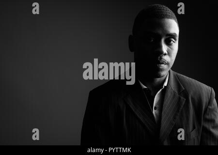 Bel giovane imprenditore africano indossare tuta contro grigio bac Foto Stock