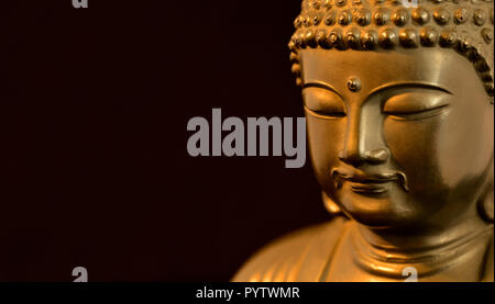 Golden BUDDA STATUETTA in atto di meditare (su sfondo nero con copia spazio) Foto Stock