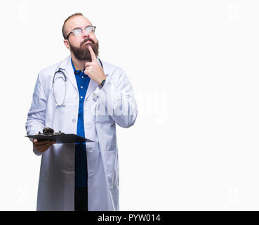 Giovane medico uomo azienda appunti su sfondo isolato faccia seriamente pensando di domanda, molto confusa idea Foto Stock