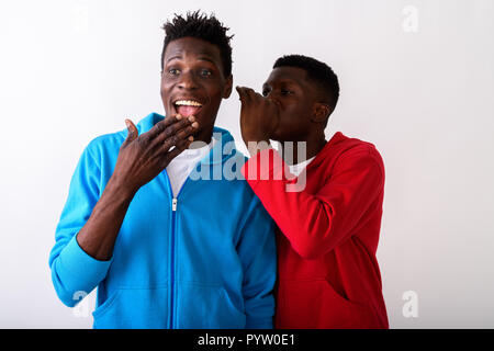 Studio shot del giovane nero africano whispering a felice slim Foto Stock