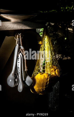 Ceramica misurini appeso accanto al sacchetto di limoni in cucina Foto Stock