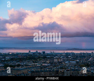 Calton Hill, Edimburgo, Scozia, Regno Unito, 30/10/2018. Regno Unito: Meteo Tramonto nel centro della città che si affaccia a nord su tenement tetti verso Fife e il Firth of Forth con bassa illuminazione sun Nuvole rosa si riflette nel mare e un arcobaleno a distanza Foto Stock