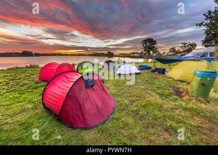 Piazzola con tende a cupola vicino al lago su un festival di musica campeggio sotto la bellissima alba Foto Stock