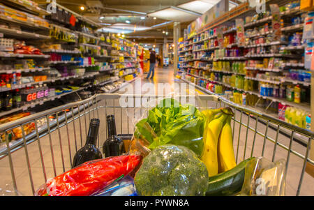 Carrello per supermercati in corrispondenza di un corridoio riempito con verdure sane visto dalla parte dei consumatori il punto di vista da sopra Foto Stock