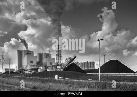 Impianti industriali pesanti con tubi e fumo e cumuli di carbone in bianco e nero Foto Stock