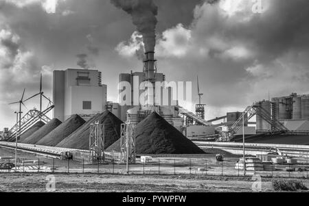 Industria pesante impianto con tubi e fumo e pile di carbone in bianco e nero Foto Stock