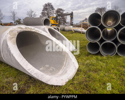 I tubi di cemento e plastica draines con altro materiale da costruzione su un sito in costruzione Foto Stock